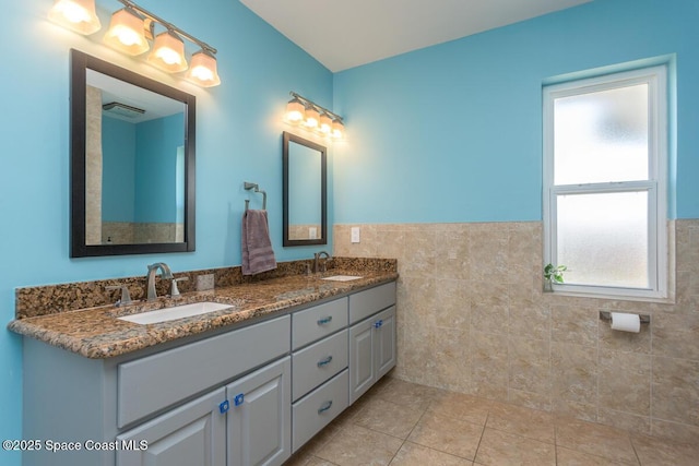 full bathroom featuring tile patterned floors, a sink, tile walls, and double vanity