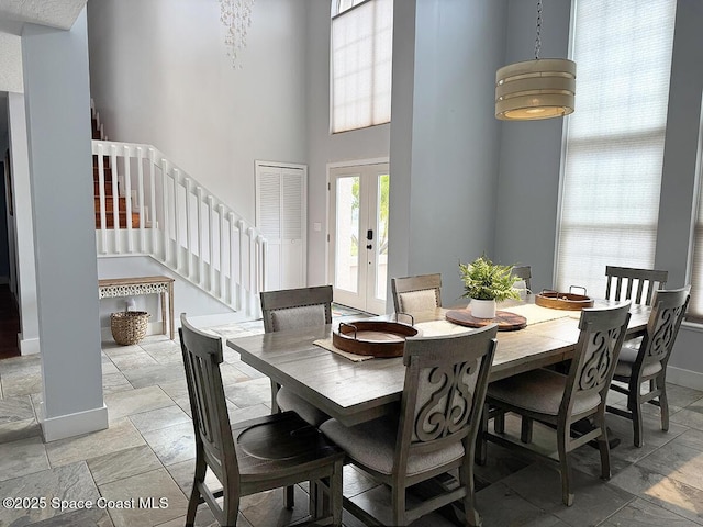 dining space featuring baseboards, stairway, stone tile flooring, and french doors