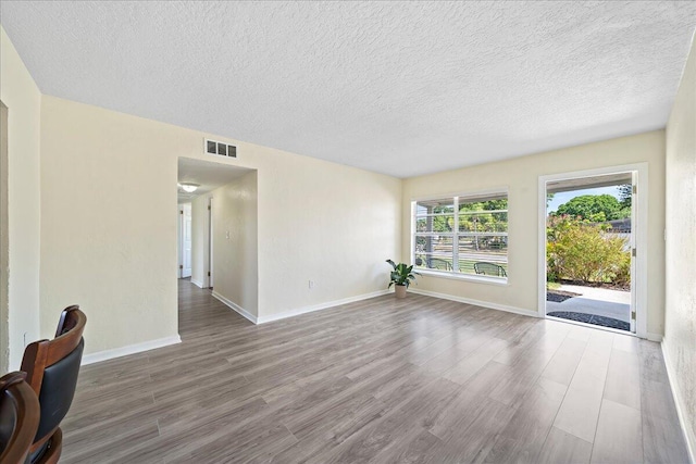 spare room featuring hardwood / wood-style floors and a textured ceiling