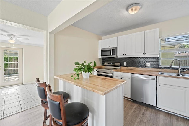 kitchen with wood-type flooring, appliances with stainless steel finishes, sink, and wood counters