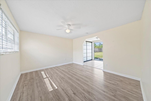 empty room with ceiling fan and light hardwood / wood-style flooring