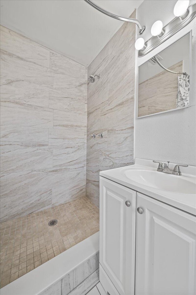 bathroom featuring tiled shower and vanity with extensive cabinet space