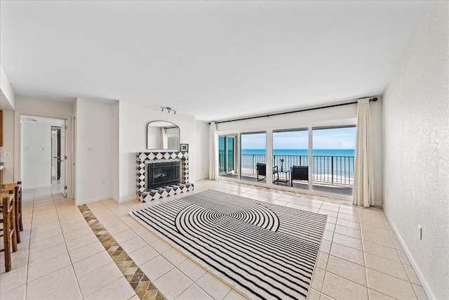 living room with a water view, light tile floors, and a tiled fireplace