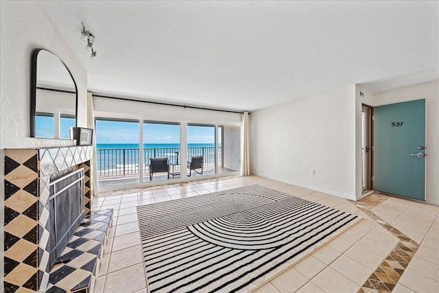 tiled living room featuring rail lighting and a water view