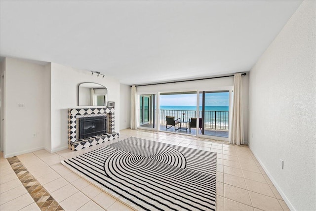 unfurnished living room with a water view, light tile floors, and a tiled fireplace