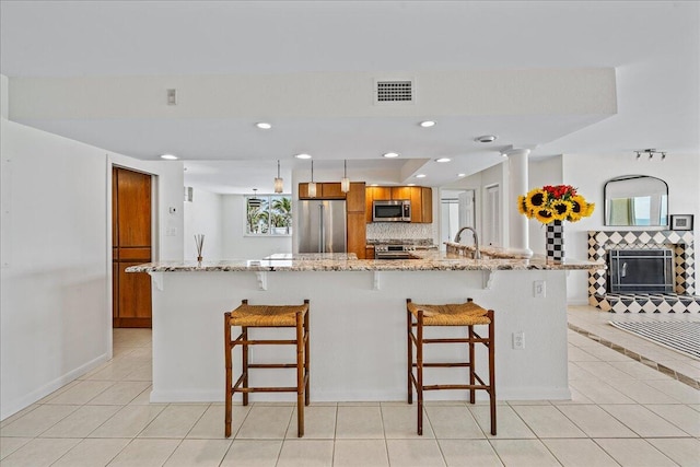 kitchen with light tile flooring, high end appliances, plenty of natural light, and light stone countertops