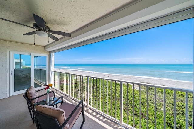 balcony featuring ceiling fan, a beach view, and a water view