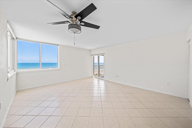 unfurnished room with a water view, ceiling fan, and light tile floors