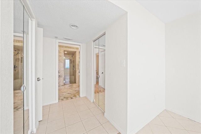 hall with light tile floors and a textured ceiling