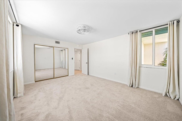 unfurnished bedroom featuring light carpet and a closet