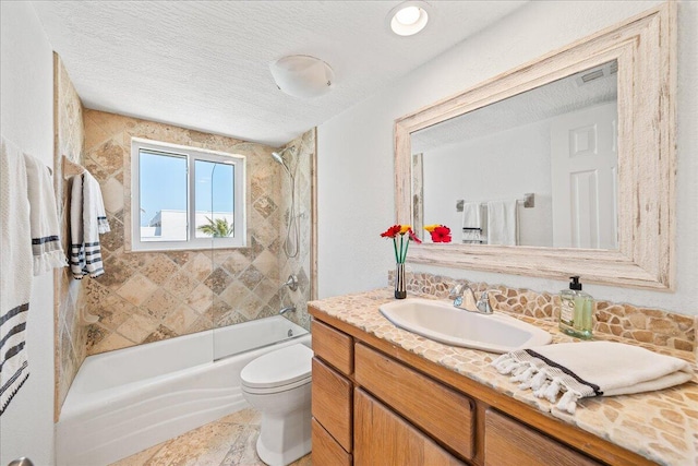 full bathroom featuring a textured ceiling, large vanity, toilet, and tiled shower / bath