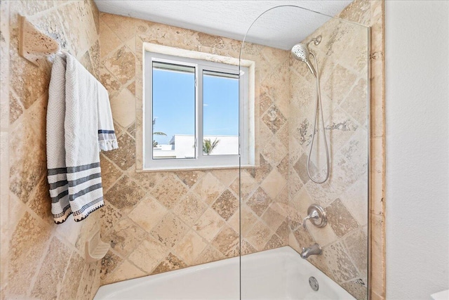 bathroom with tiled shower / bath and a textured ceiling