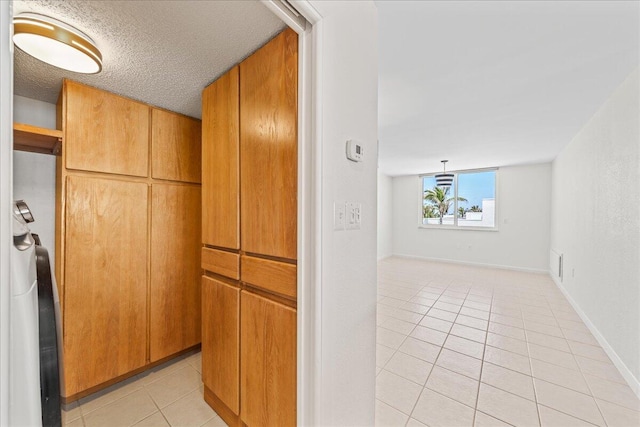 kitchen with decorative light fixtures, light tile floors, and a textured ceiling