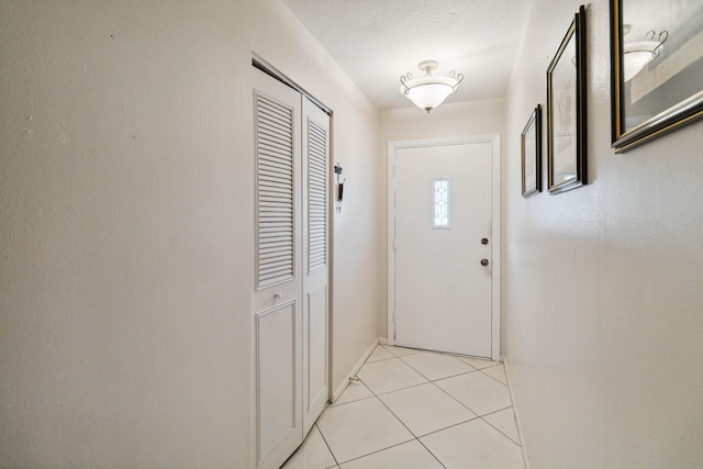 doorway featuring light tile floors and a textured ceiling