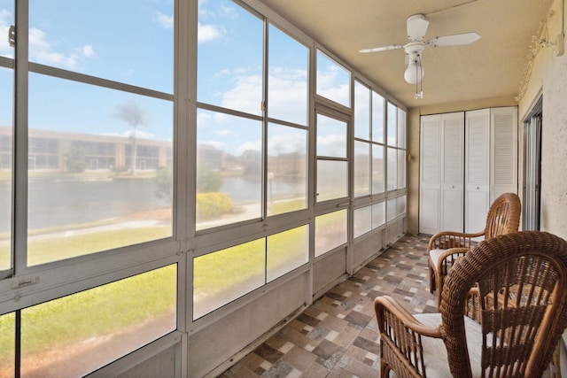 sunroom featuring a water view and ceiling fan