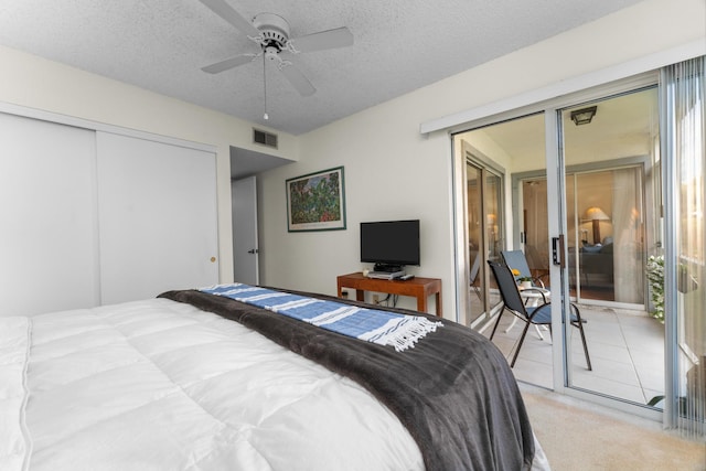 bedroom with ceiling fan, light colored carpet, a textured ceiling, and a closet