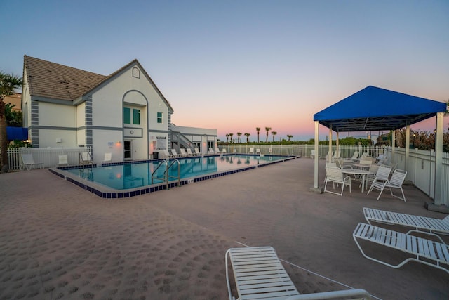 pool at dusk featuring a patio