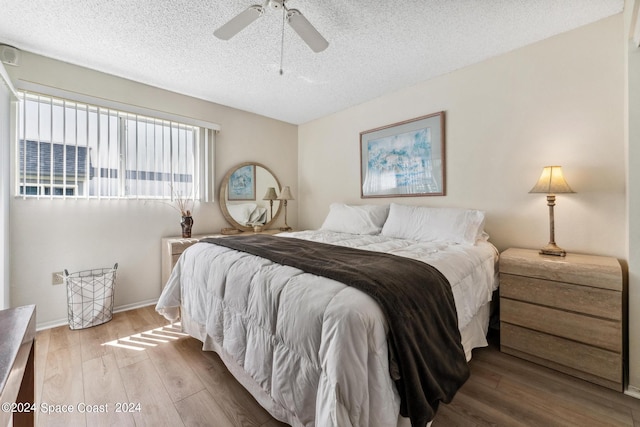 bedroom with a textured ceiling, wood-type flooring, and ceiling fan