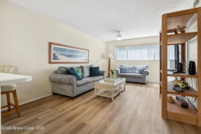 living room with light hardwood / wood-style flooring, ceiling fan, and a textured ceiling