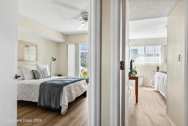 bedroom featuring light wood-type flooring, multiple windows, and ceiling fan