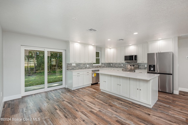 kitchen with appliances with stainless steel finishes, tasteful backsplash, a center island, dark hardwood / wood-style floors, and white cabinetry