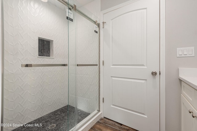 bathroom with hardwood / wood-style floors, vanity, and an enclosed shower