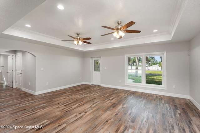 unfurnished room featuring a raised ceiling, crown molding, and dark hardwood / wood-style flooring