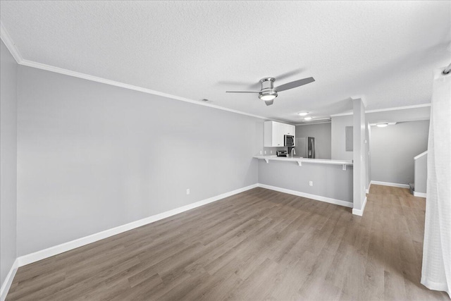 unfurnished living room featuring hardwood / wood-style floors, ceiling fan, ornamental molding, and a textured ceiling