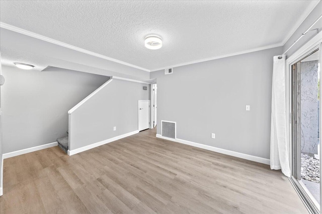 unfurnished living room featuring light hardwood / wood-style floors, crown molding, and a textured ceiling