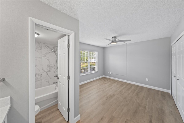 empty room with light hardwood / wood-style flooring, ceiling fan, and a textured ceiling