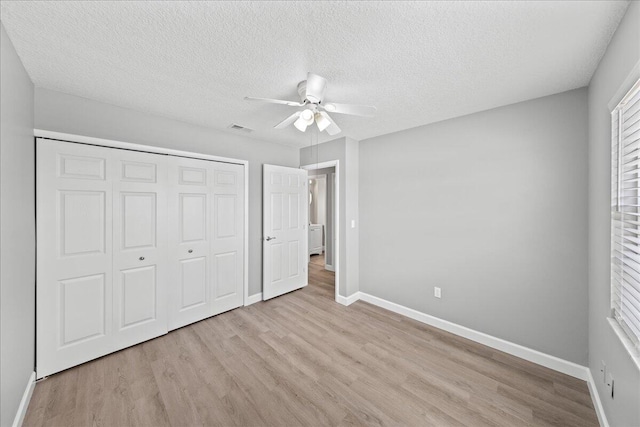 unfurnished bedroom featuring a closet, ceiling fan, light wood-type flooring, and a textured ceiling