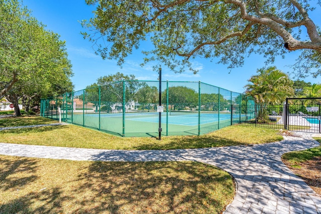 view of tennis court with a yard