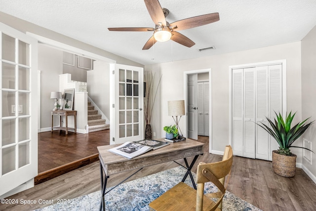 home office featuring a textured ceiling, ceiling fan, dark wood-type flooring, and french doors