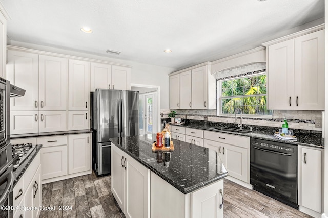 kitchen with a kitchen island, sink, dishwasher, white cabinetry, and stainless steel refrigerator