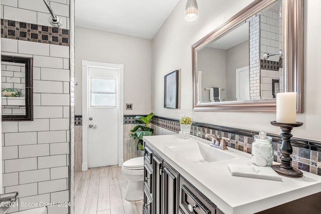 bathroom featuring wood-type flooring, vanity, toilet, and tile walls