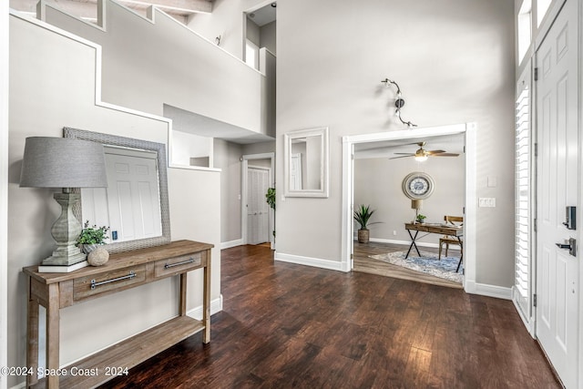 entrance foyer with a towering ceiling, ceiling fan, and dark wood-type flooring