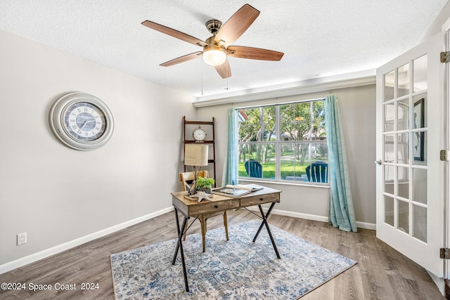 home office featuring ceiling fan, wood-type flooring, a textured ceiling, and french doors