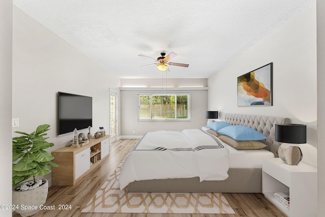 bedroom with ceiling fan, light hardwood / wood-style flooring, and a textured ceiling