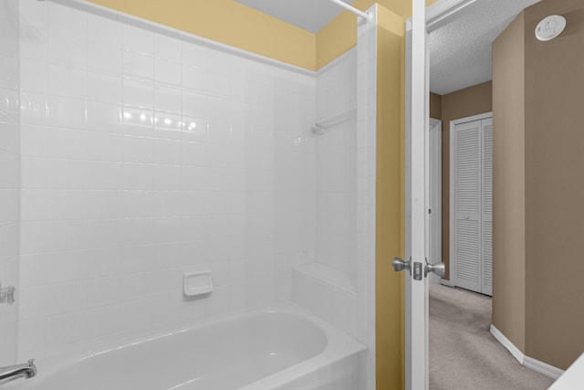 bathroom with a textured ceiling and tiled shower / bath