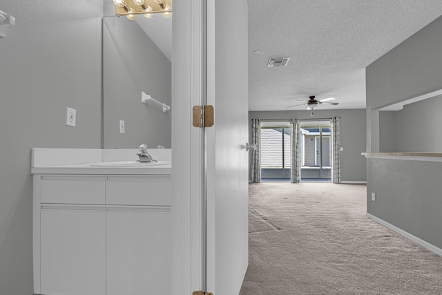 bathroom with visible vents, baseboards, ceiling fan, a textured ceiling, and vanity