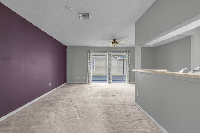 unfurnished room with light carpet, ceiling fan, and a textured ceiling