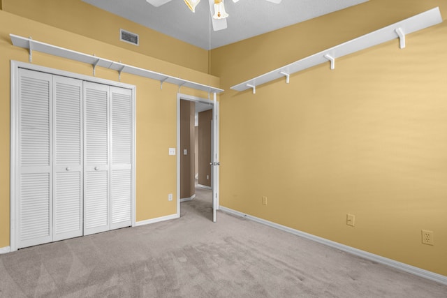 unfurnished bedroom with a ceiling fan, visible vents, baseboards, a closet, and carpet