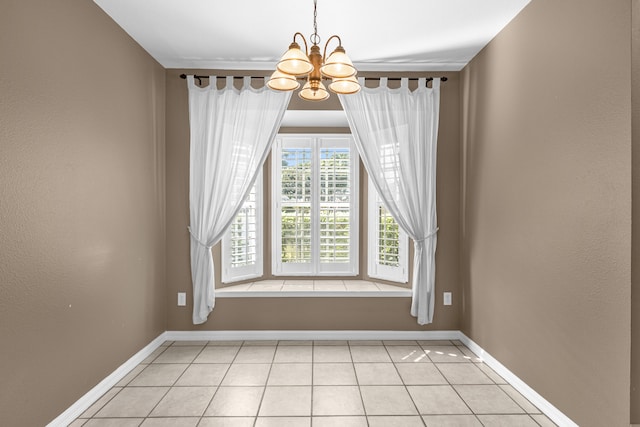 empty room featuring baseboards, a chandelier, and light tile patterned flooring