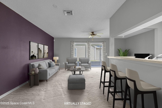 living room with baseboards, visible vents, a textured ceiling, and carpet flooring