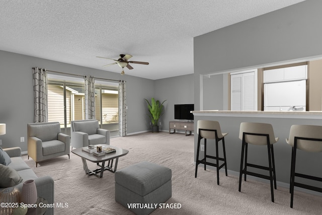 carpeted living room with ceiling fan, a textured ceiling, and baseboards