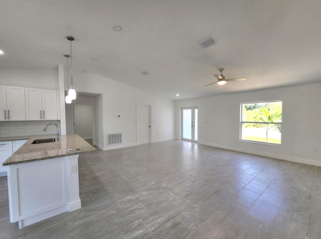 kitchen with light tile floors, sink, backsplash, decorative light fixtures, and lofted ceiling