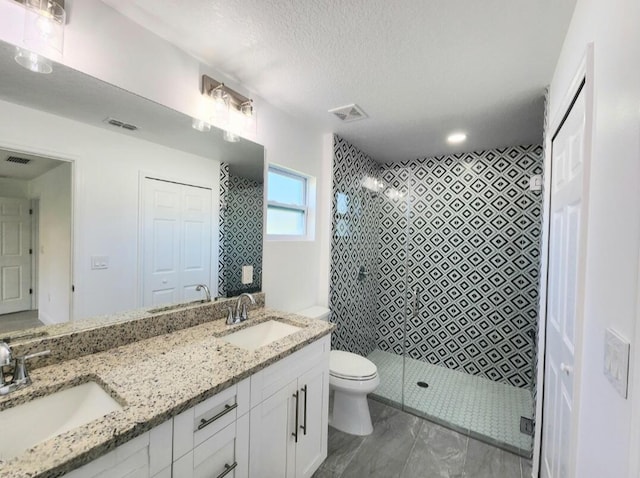 bathroom featuring an enclosed shower, tile floors, double sink vanity, toilet, and a textured ceiling