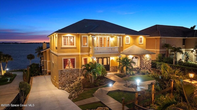 view of front of property with a balcony, stone siding, and stucco siding