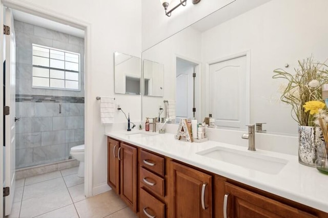 bathroom featuring tile floors, dual bowl vanity, toilet, and a tile shower