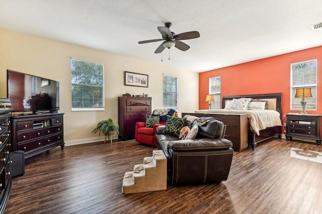 bedroom featuring dark hardwood / wood-style flooring, multiple windows, and ceiling fan